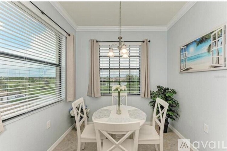 A dining room with a table set for two and a painting on the wall.