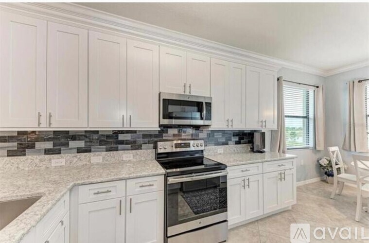 A kitchen with white cabinets and a granite countertop.