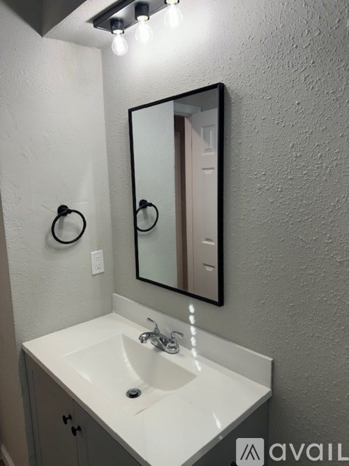 A bathroom with a white sink and a mirror above it.