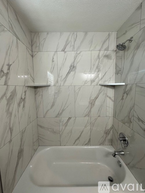 A bathroom with a marble tile wall and a white bathtub.