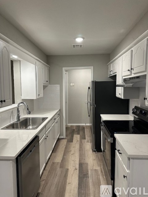 A kitchen with white cabinets and a black refrigerator.