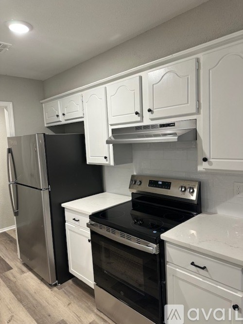 A kitchen with white cabinets and black appliances.