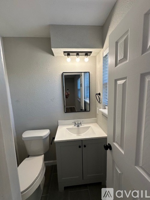 A bathroom with a toilet, sink, and mirror.