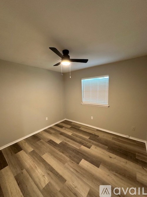 A room with a ceiling fan and wooden flooring.