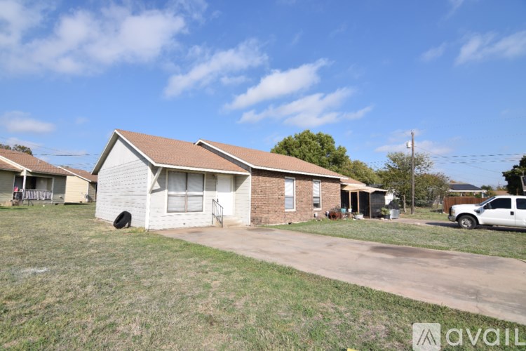 A house with a white front yard and a white pickup truck parked in the driveway.