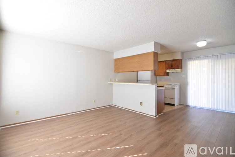 A spacious room with wooden flooring and a white cabinet with a countertop.