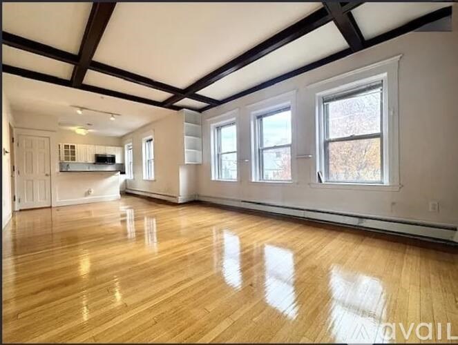 A spacious room with wooden floors and large windows.