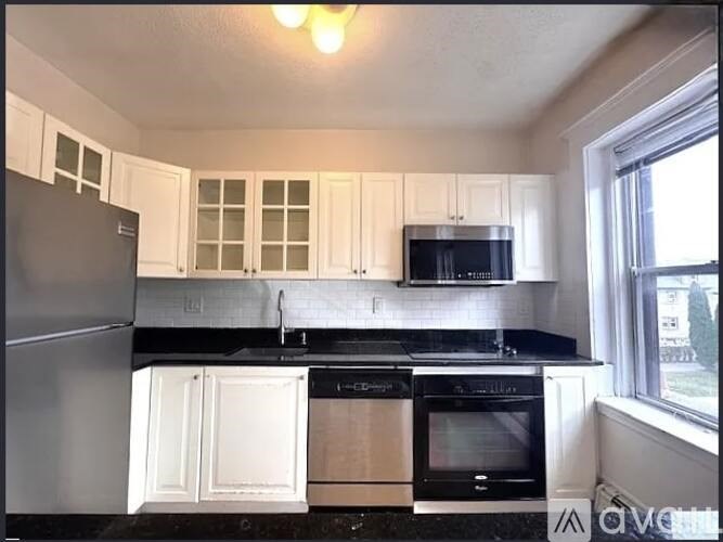 A kitchen with white cabinets and black appliances.
