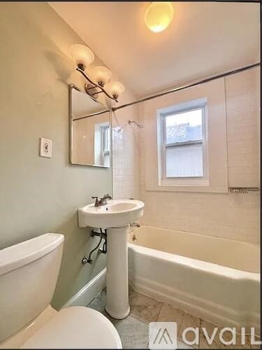 A bathroom with a white tub, sink, and toilet.