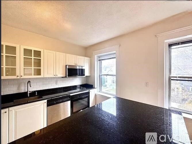 A kitchen with black countertops and white cabinets.
