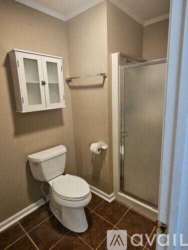A white toilet sits in a bathroom next to a glass shower door.