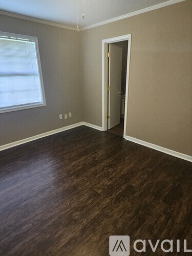 A room with a wooden floor and a door leading to another room.