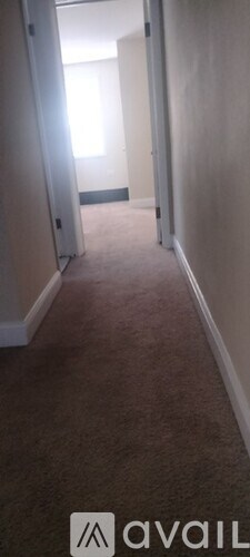 A hallway with carpeted flooring and white walls.