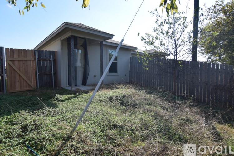 A house with a fence and a tree in front of it.