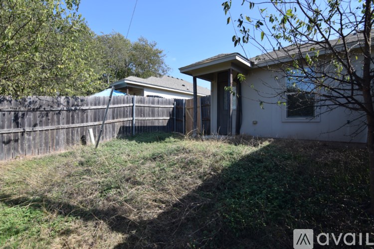 A house with a fence and a tree in front of it.