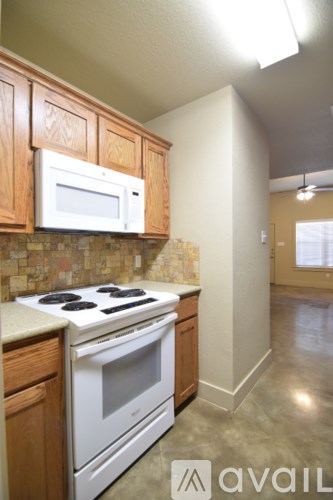 A kitchen with a white stove and oven, wooden cabinets, and a tiled backsplash.