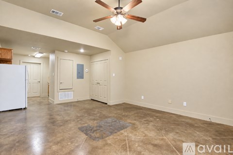 A spacious room with a ceiling fan and a rug on the floor.