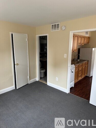 A room with a door, a window, and a kitchen area.