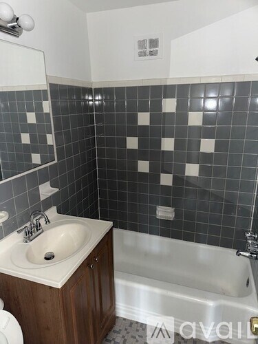 A bathroom with a white sink and a black and white tiled wall.