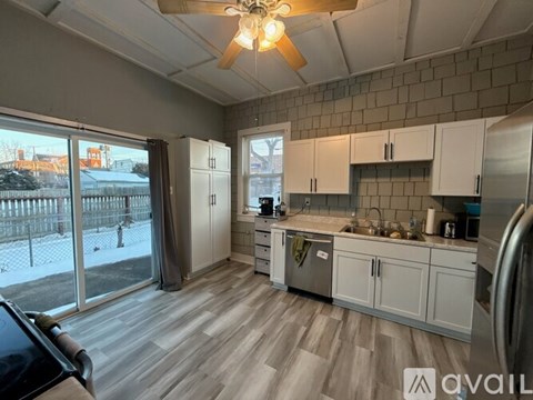 A kitchen with white cabinets and a ceiling fan.