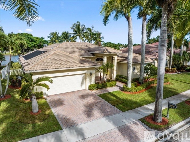 A house with a driveway and palm trees in front.
