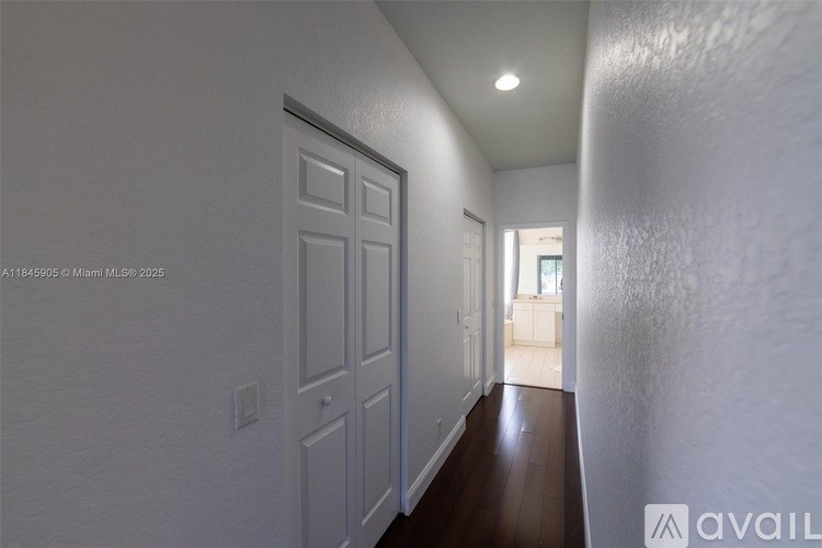 A long hallway with a door on the left and a window on the right.