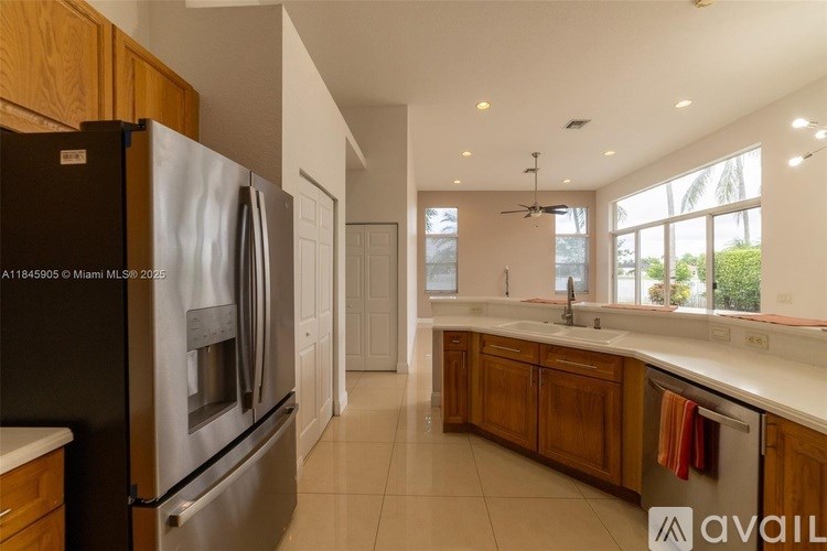 A kitchen with a black refrigerator and wooden cabinets.