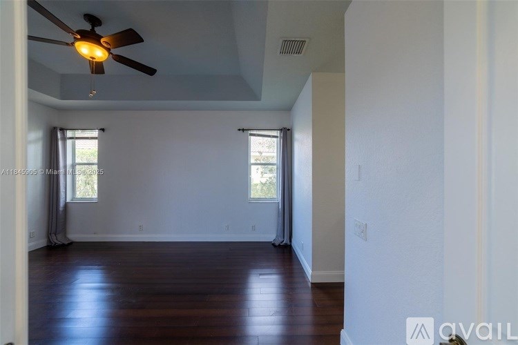 A room with a ceiling fan and wooden floors.
