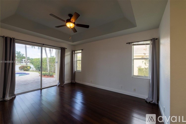 A spacious room with a ceiling fan and sliding glass doors leading to a pool area.