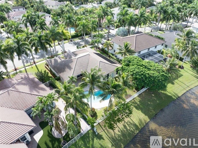 A bird's eye view of a house surrounded by palm trees and a pool.