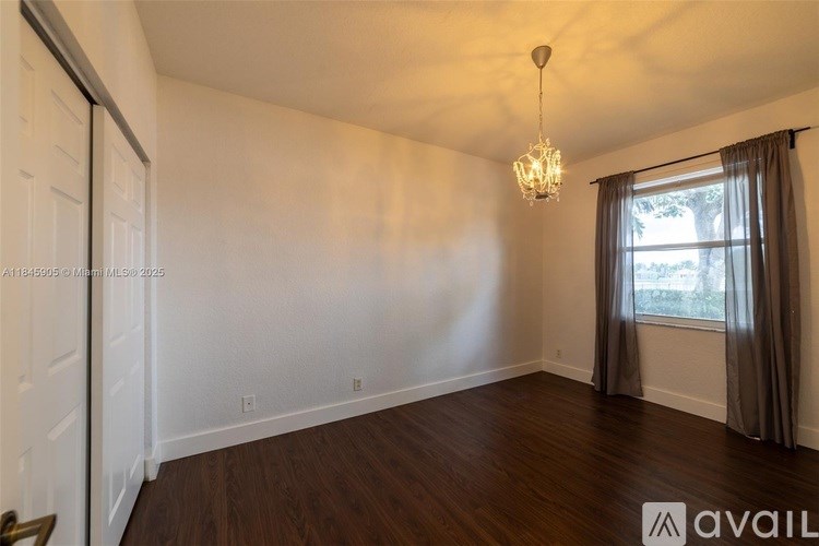 A room with a chandelier and a window with curtains.