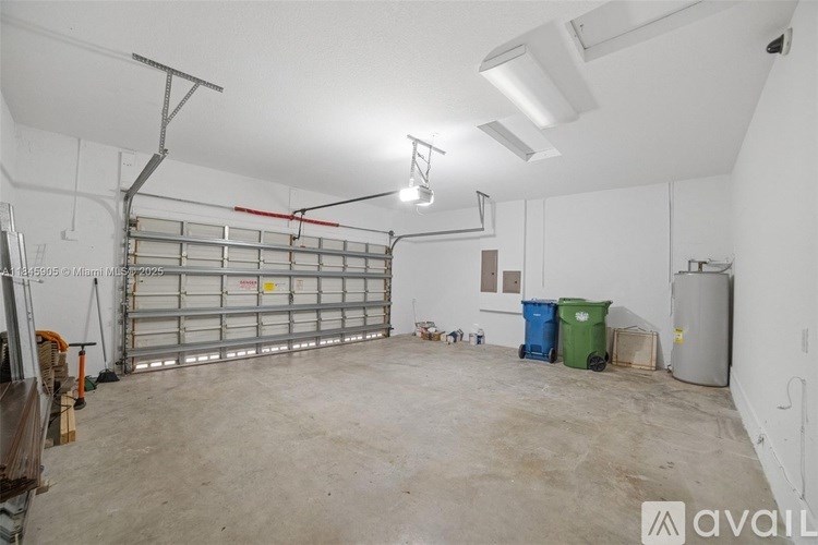 A large, empty garage with a white ceiling and walls, a metal shelving unit, and a few items scattered around.