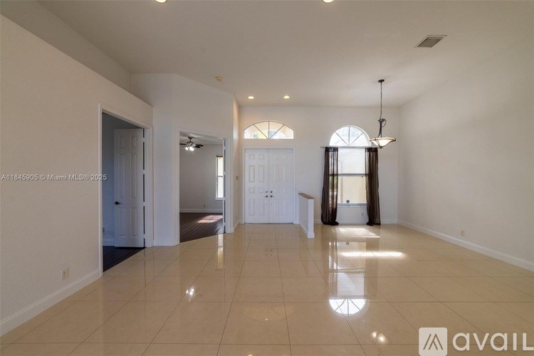 A spacious living room with a large window and a chandelier.