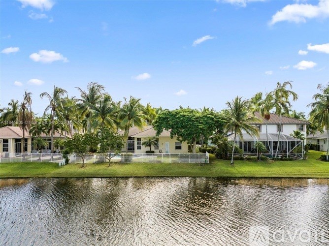 A serene lakeside view with houses and palm trees.