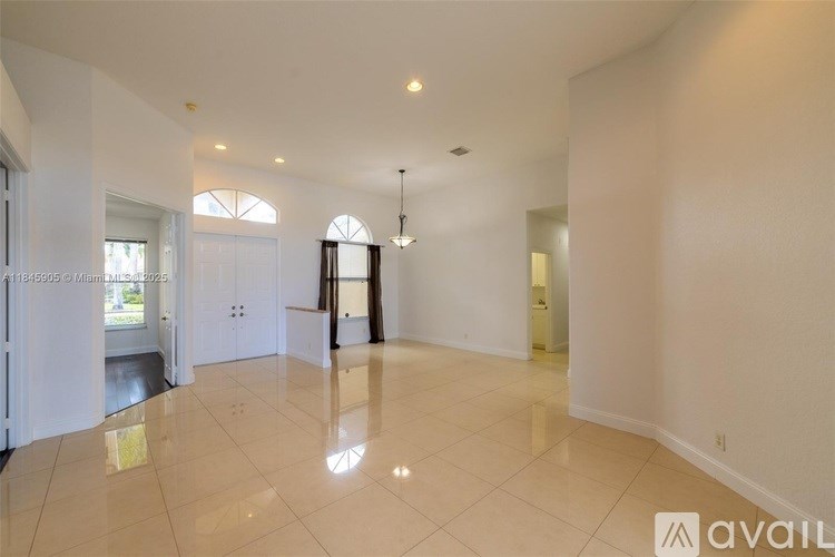 A spacious, empty room with a large tiled floor and white walls.