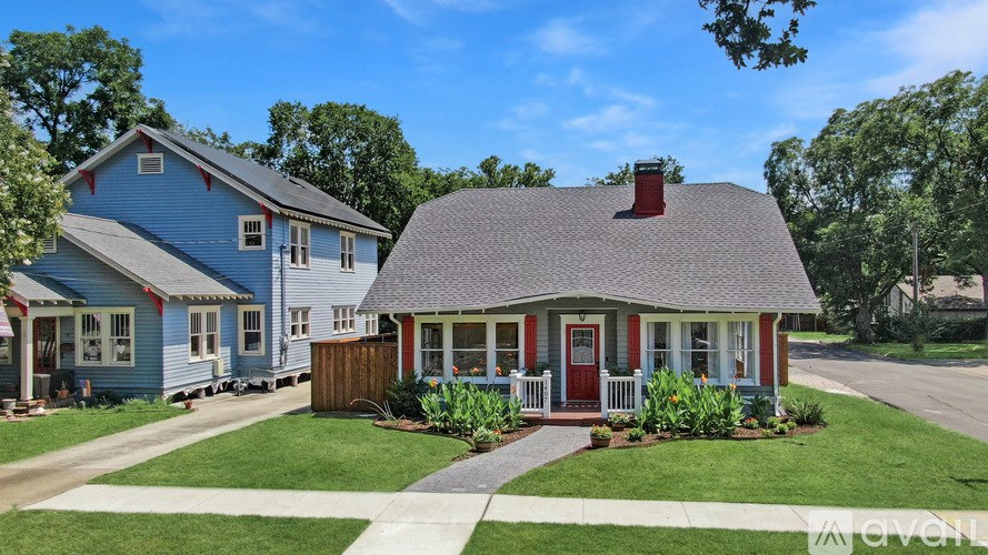 A blue house with a red door and a grey roof.