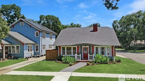 A blue house with a red door and a grey roof.