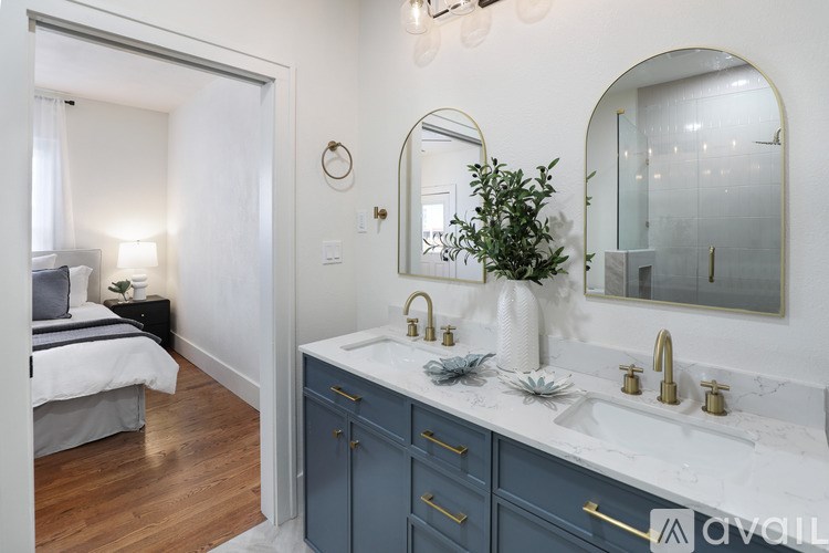 A bathroom with a double sink vanity and a bedroom area.