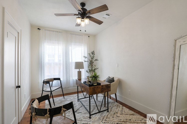 A living room with a ceiling fan, a table with chairs, and a plant.