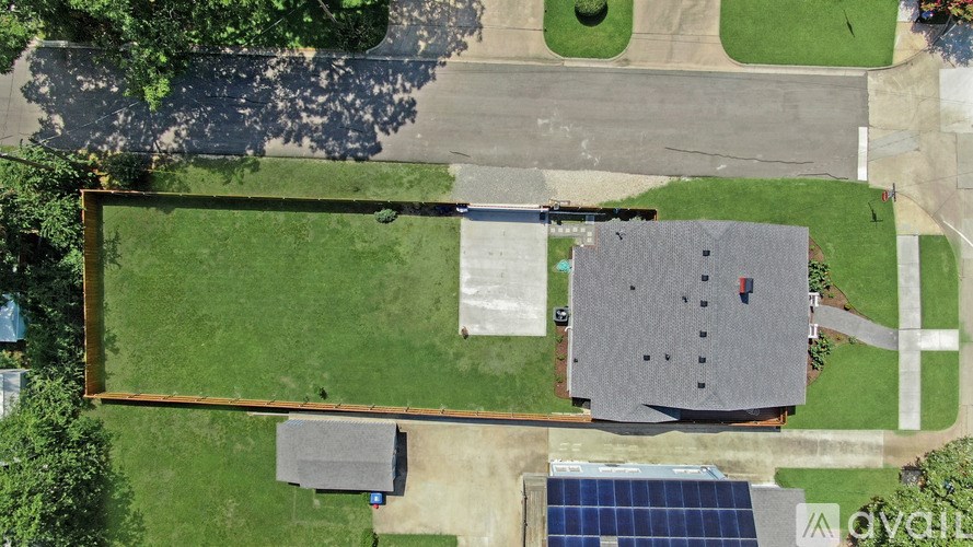 A house with a solar panel on the roof and a fence surrounding it.