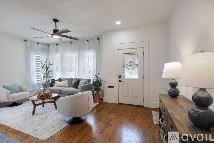 A living room with a fan, a couch, a chair, a table, and a lamp.