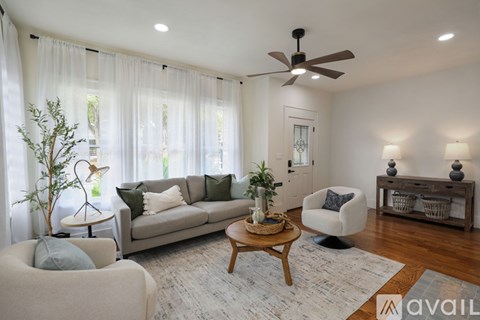 A living room with a couch, chair, and a table with a plant on it.