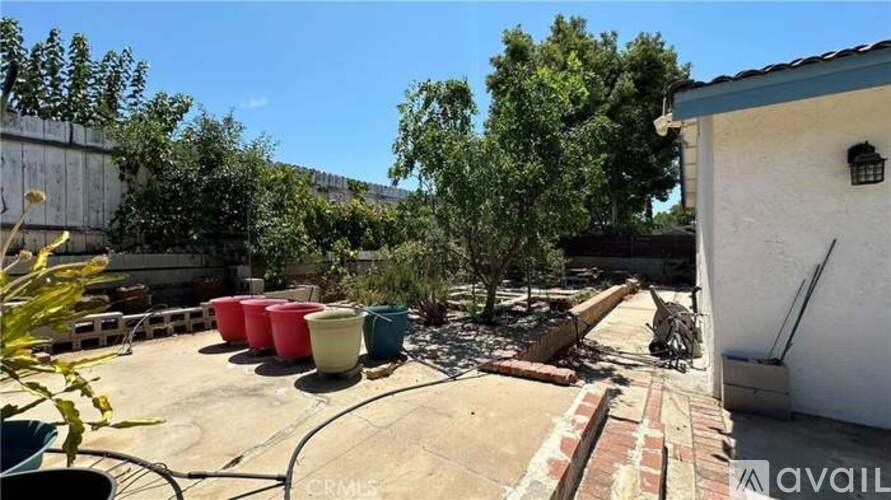 A backyard with a white house, a red fire hydrant, and a green lawn.