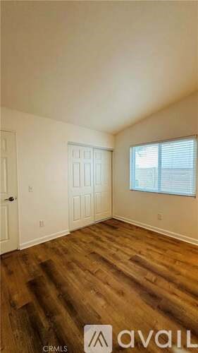 A room with wooden floors and a window with blinds.