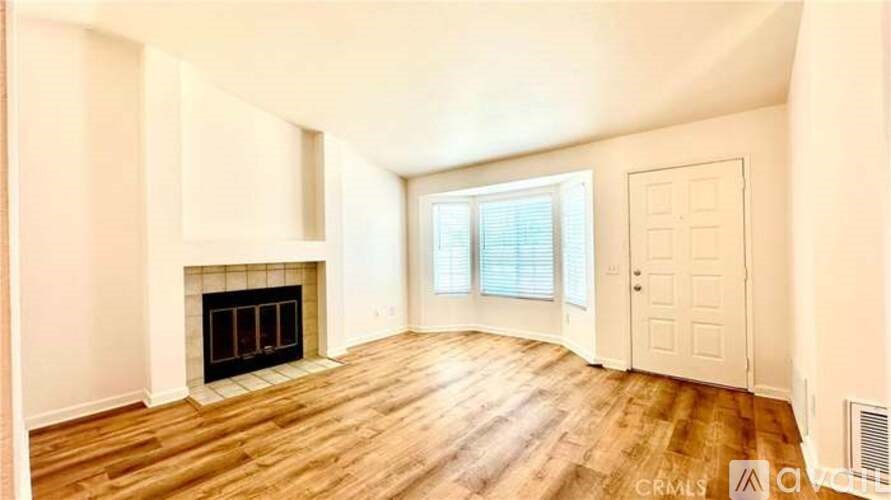 A spacious room with a fireplace and wooden flooring.
