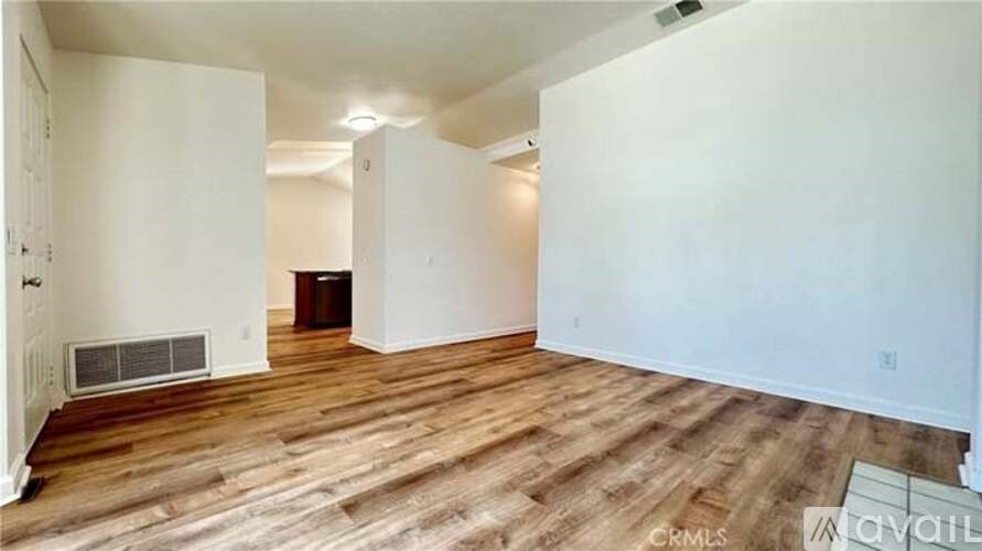 A spacious room with wooden flooring and white walls.