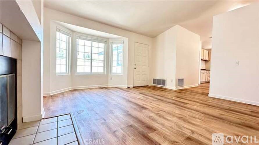 A spacious room with wooden flooring and a large window.