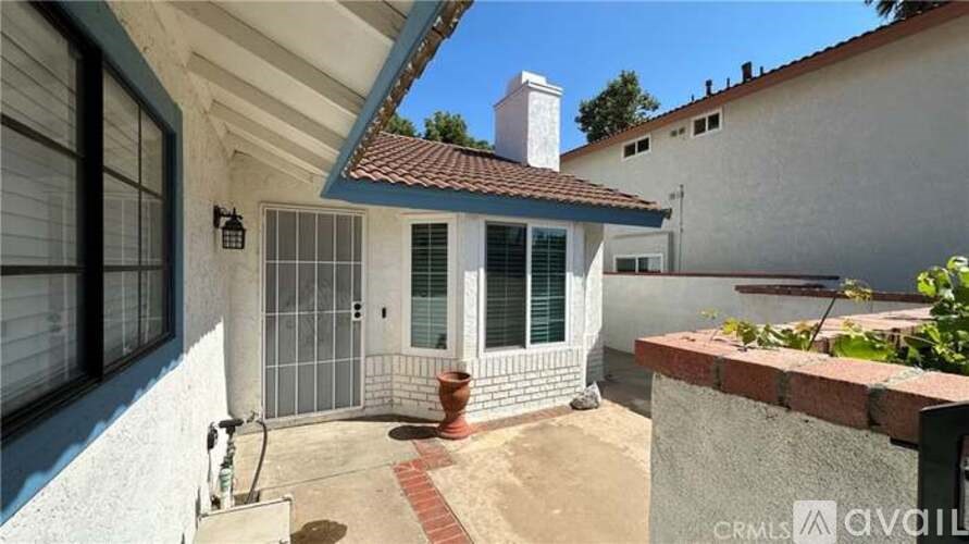 A house with a red roof and a white wall with a gate and a window.