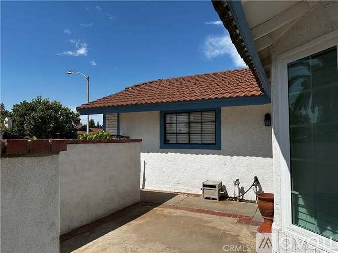A white house with a red tile roof and a blue window.