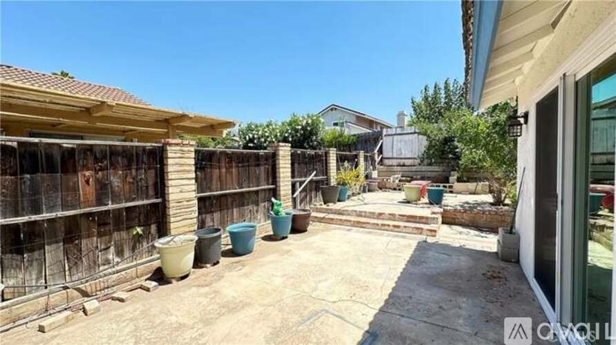 A backyard with a wooden fence and a few potted plants.